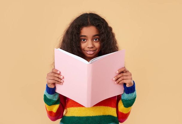 Smiling ethnic schoolgirl reading book - Fotó, kép