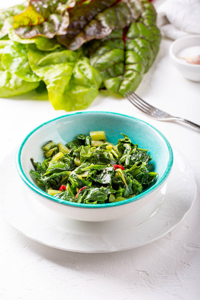 Bowl of fried chard leaves on white background. Vegetarian or vegan diet, healthy food concept. - 写真・画像
