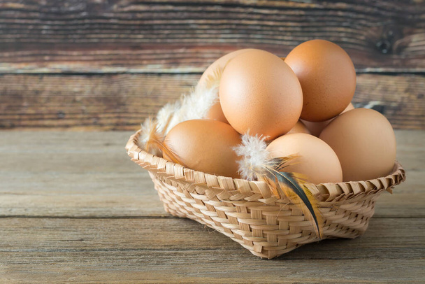 Farm fresh eggs in a basket on a wooden table. There is a wooden background. - Foto, imagen