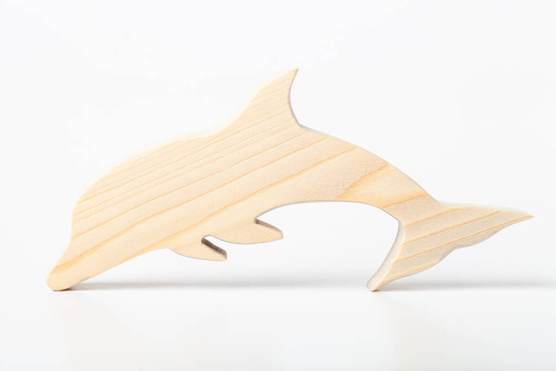 Dolphin figurine carved from solid pine by hand jigsaw. On a white background . - Фото, изображение