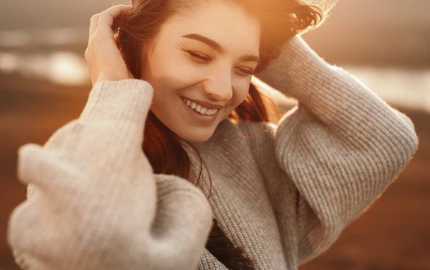 Happy woman in sweater enjoying sunny autumn day in nature - 写真・画像