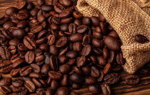 Roasted coffee beans on the old dark wooden background for wallpaper or decor. - Foto, afbeelding