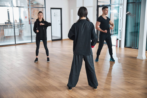 Woman coach watching over two martial arts learners - Photo, Image
