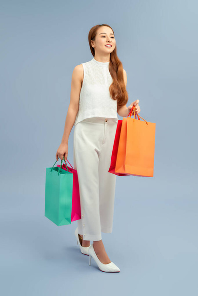 women holding shopping bags in her hands feeling so happiness isolated on blue background with a copy space - Фото, зображення