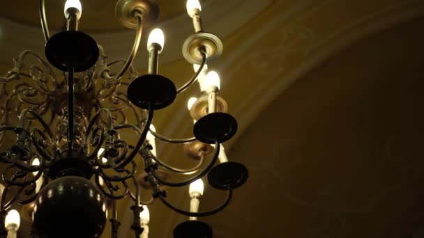 Black metal chandelier in baroque style with ceiling and candle light bulbs. - Footage, Video