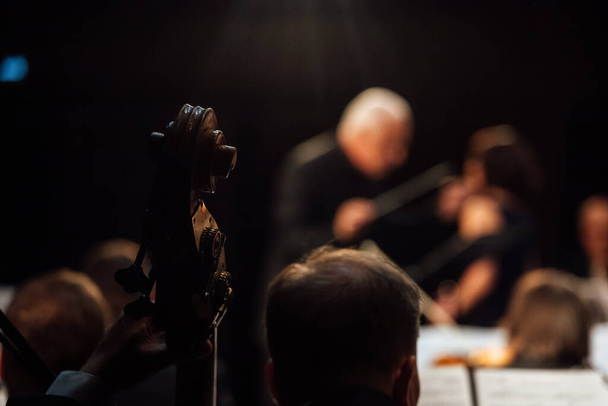 μαέστρος στο σκοτάδι. Ένας άντρας με επίσημο κοστούμι ελέγχει τους μουσικούς της ορχήστρας. συμφωνική μουσική συναυλία - Φωτογραφία, εικόνα