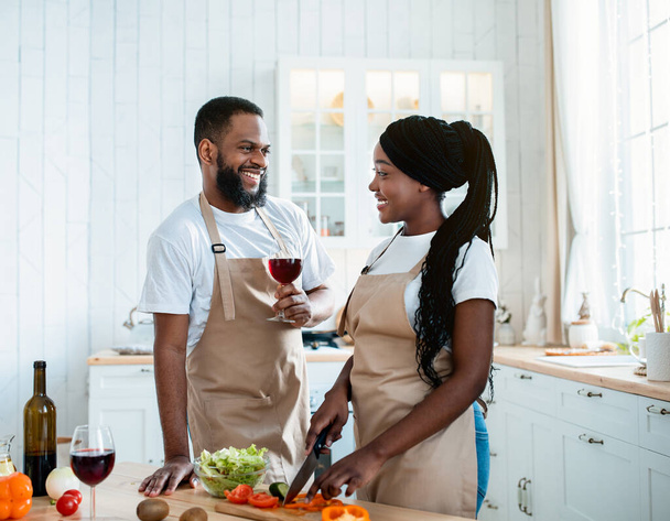 Boldog afrikai házastársak főzés egészséges ebéd és ivás vörös bor a konyhában - Fotó, kép