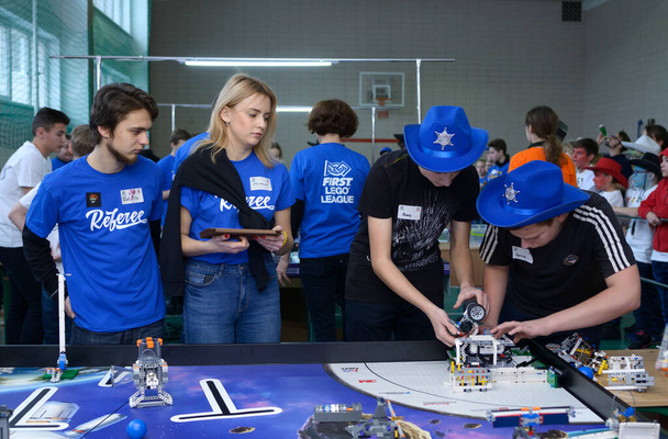 Młodzi ludzie dostosowują się do robotów przed ich uruchomieniem. Turniej szkolny wśród uczniów. 9 stycznia 2019. Kijów, Ukraina - Zdjęcie, obraz