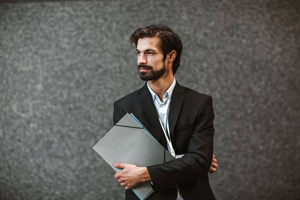 Young happy businessman holding clipboard outside of modern building - Photo, Image