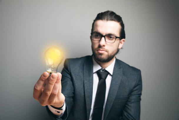 man holding a glowing lamp. concept idea on gray background - Valokuva, kuva