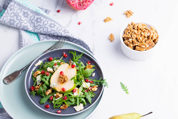 Vers en gezond salade met arugula, gorgonzola kaas, granaatappel en peren. - Foto, afbeelding