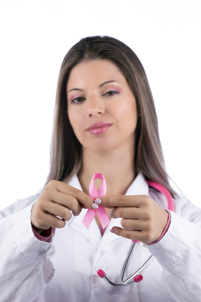 młoda piękna lekarz kobieta z różowym stetoskopem i różową wstążką świadomości raka piersi na białym tle. - Zdjęcie, obraz