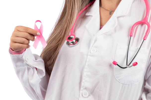 jeune belle médecin femme avec stéthoscope rose et ruban de sensibilisation rose pour le cancer du sein sur un fond blanc. - Photo, image