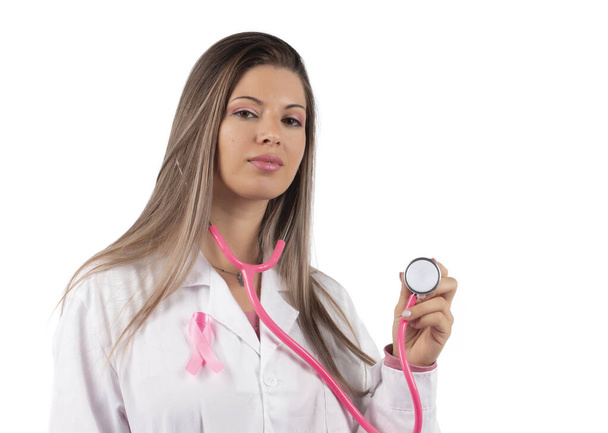 giovane bella donna medico con stetoscopio rosa e nastro di consapevolezza rosa per il cancro al seno su uno sfondo bianco. - Foto, immagini