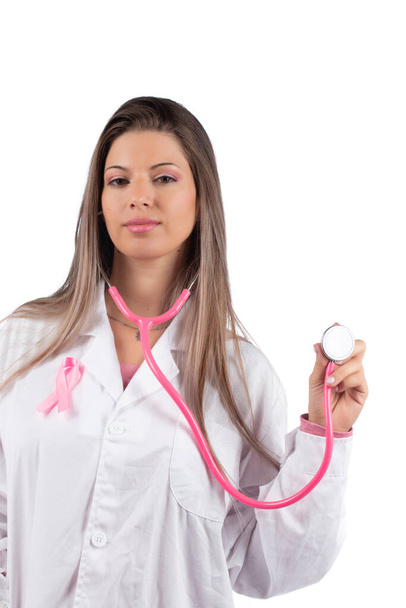 fiatal gyönyörű orvos nő rózsaszín sztetoszkóppal és rózsaszín tudatosság szalag mellrák fehér alapon. - Fotó, kép