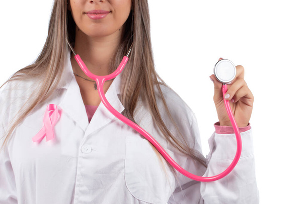 ピンクの聴診器とピンクの意識リボンを持つ若い美しい医師の女性乳がんのための白い背景. - 写真・画像