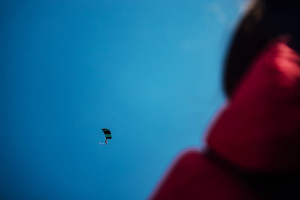 siluetas de los espectadores sobre el fondo de los paracaidistas de aterrizaje. demostraciones de paracaidistas saltando desde un avión desde una gran altura. festival de deportes extremos - Foto, imagen