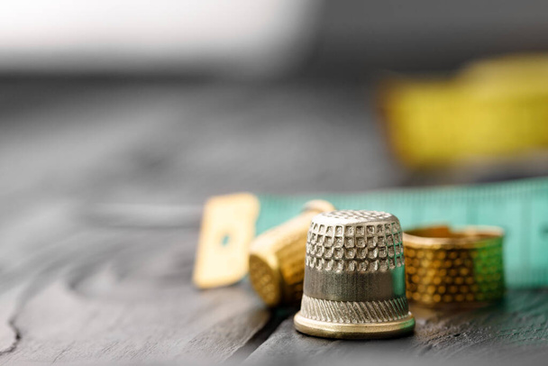 Thimble and measuring tape on wooden table - Foto, afbeelding