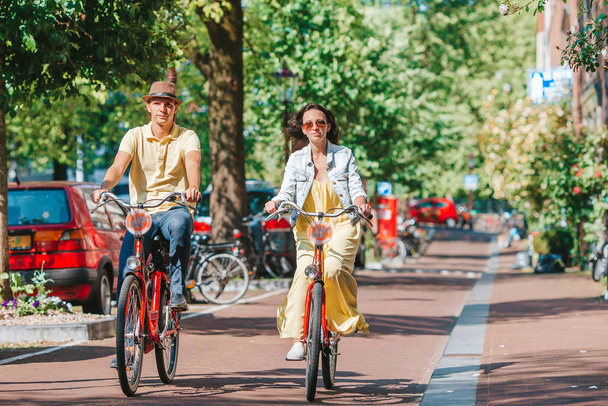 Giovane coppia caucasica felice in bicicletta nelle vecchie strade di Amsterdam - Foto, immagini