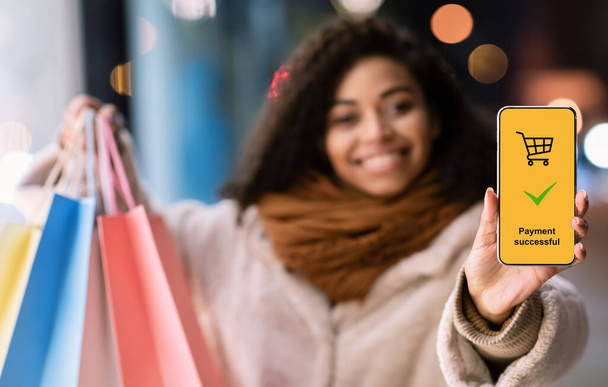 支払い成功画面とスマートフォンを示す幸せな黒人女性 - 写真・画像
