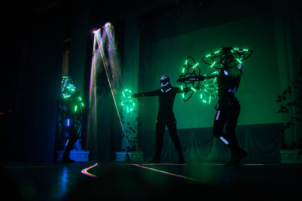 an incredible beauty of the performance of artists and dancers on stage, a fireshow with LED suits and lasers reflecting on a lot of mirror details in clothes, iridescent with all the colors - Photo, Image