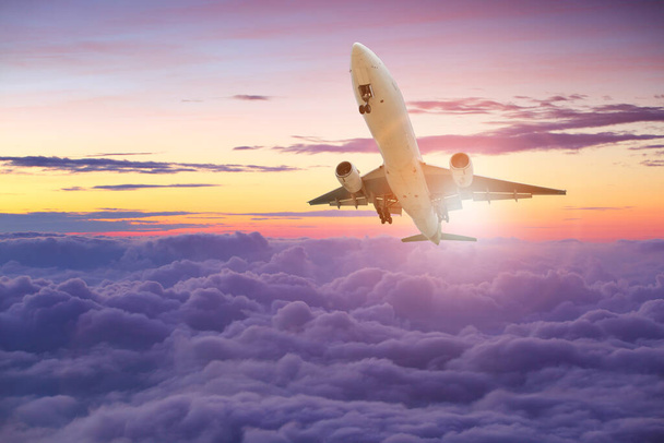 Μεγάλο λευκό αεροπλάνο πετά πάνω από τα σύννεφα με πολύχρωμο ουρανό στο ηλιοβασίλεμα για Επαγγελματικό ταξίδι με Εμπορικό αεροπλάνο, Μεταφορές, εισαγωγές-εξαγωγές και logistics, Ταξιδιωτική ιδέα, Αεροπλάνο πετάει για Επαγγελματικό ταξίδι, Μεταφορές, εισαγωγές-εξαγωγές, logis - Φωτογραφία, εικόνα