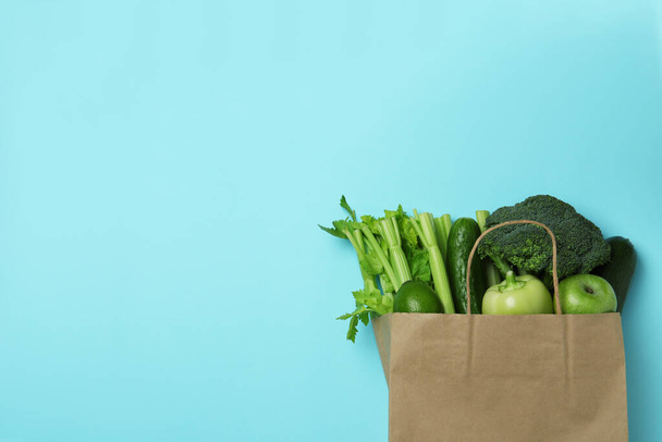 Paper bag with green vegetables on blue background - Foto, Bild