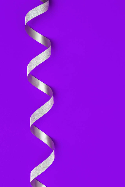 Decorative silver ribbon on proton purple background with copy space. Greeting card for Birthday, anniversary holiday. Gift voucher. - Foto, Imagem