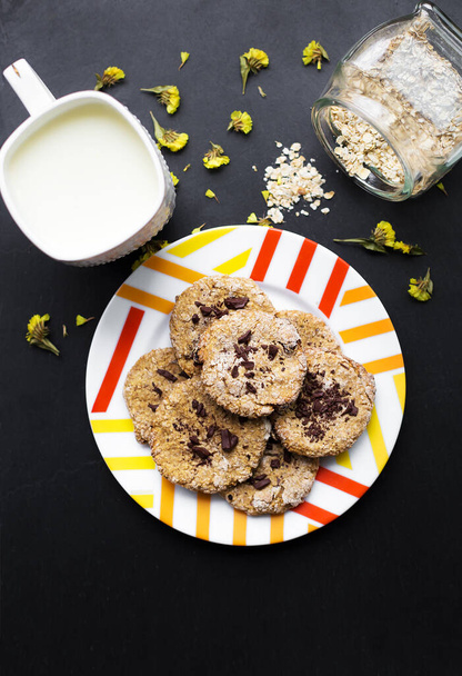 Biscotti di farina d'avena con cioccolato su un piatto con latte colorato tazza - Foto, immagini