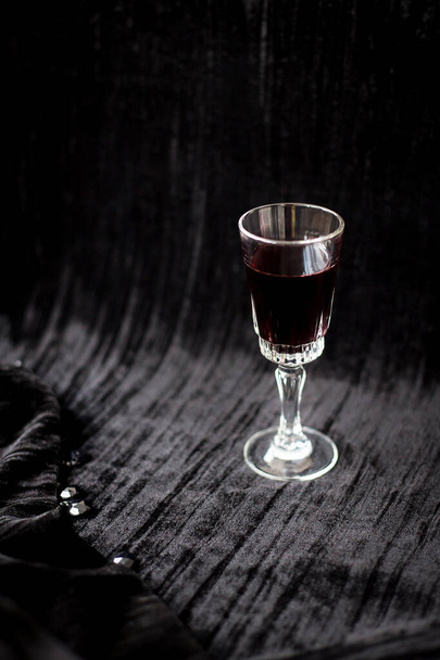 copa de vino tinto sobre un fondo de terciopelo negro, primer plano. - Foto, Imagen