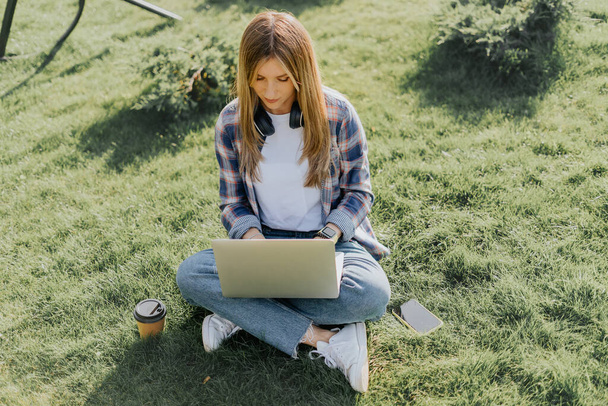 Vrouw met laptop zittend op het gras - Foto, afbeelding