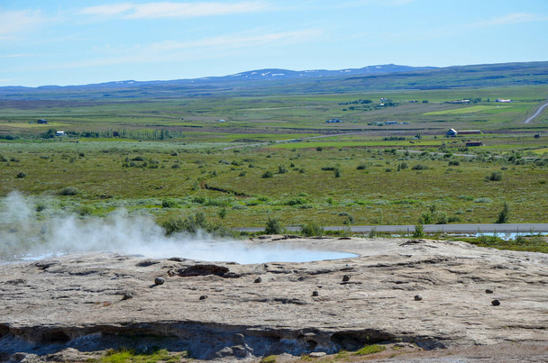 Boční pohled na geotermální louži v poli, z níž vychází termální plyn - Fotografie, Obrázek