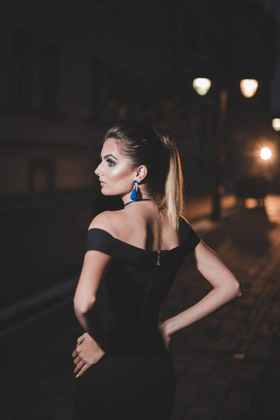A vertical shot of a Bosnian woman wearing an elegant black dress outdoors at night - Fotoğraf, Görsel
