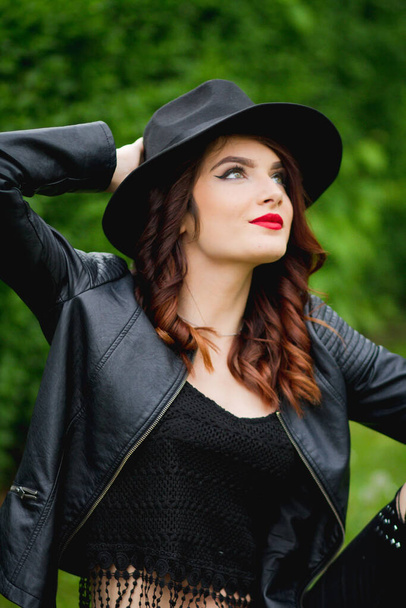 A young Bosnian stylish woman with red lipstick and a hat posing in the park - 写真・画像