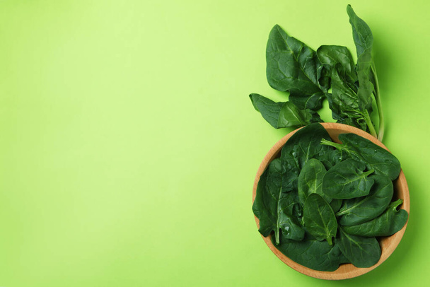 Bowl of spinach leaves on green background - Фото, зображення