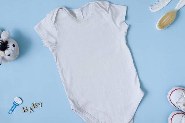子供服のフラットレイアウト。青い背景に白い赤ん坊のボディスーツのモックアップ。デザインやロゴの配置 - 写真・画像