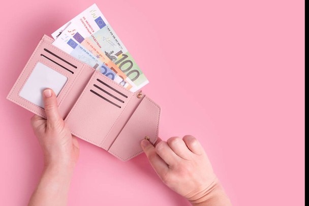 Hands holding wallet. Pink leather wallet with euro money in female hands. Closeup on a woman's hands taking European bank notes out of purse and counting. Concept of money, finances, shopping, cash - Photo, Image