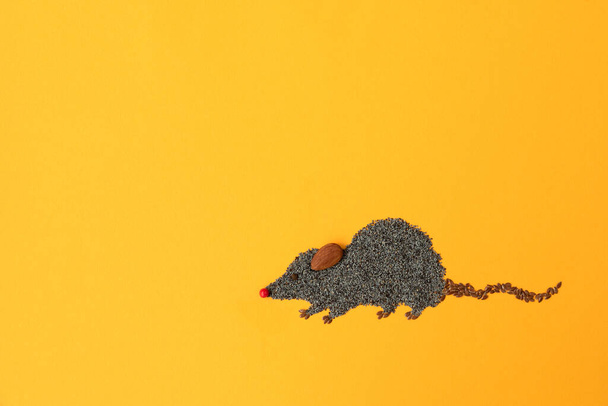 Cute mouse made of flax and poppy seeds on yellow background. Food art creative concept - Фото, зображення