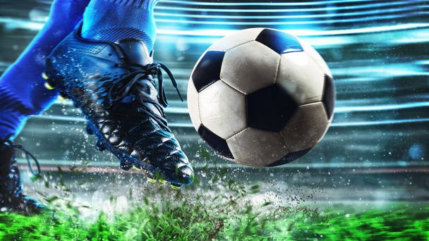 Футбольная сцена в ночном матче с крупным планом футбольной обуви, ударяющей по мячу с силой - Фото, изображение