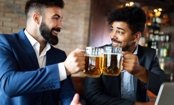 People, men, leisure, friendship and celebration concept. Happy business male friends drinking beer at pub - Foto, Imagem