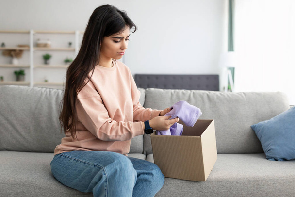 Sad young woman unpacking wrong parcel, delivery mistake - Φωτογραφία, εικόνα