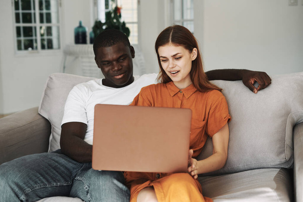 woman and man with laptop sitting on sofa friends family - Foto, Bild