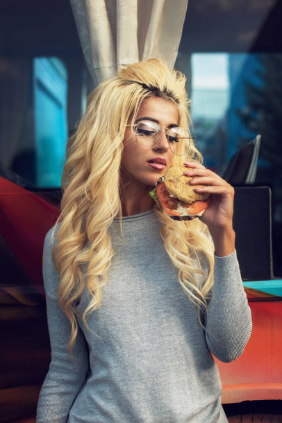 Mulher comendo um hambúrguer e água com gás perto do caminhão de alimentos - Foto, Imagem