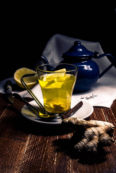 Coupe en verre avec gingembre et thé au citron, sur table en bois et théière bleue. Concept d'homéopathie et de médecine traditionnelle - Photo, image