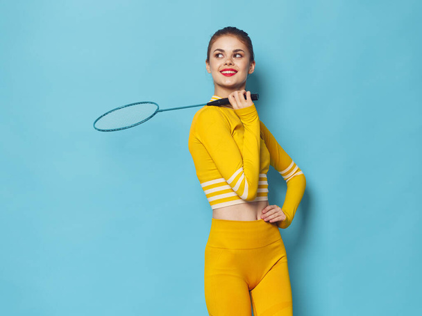 sporty woman in yellow sweater and jeans with badminton racket in hand - Fotoğraf, Görsel