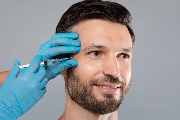 Lähikuva onnellinen komea parrakas mies saada silmään injektio - Valokuva, kuva