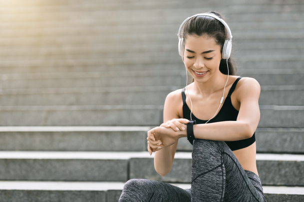 Smiling Asian Girl Setting Fitness App On Smartwatch Before Training Outdoors - Foto, Imagem
