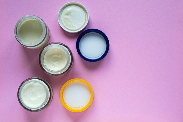 Top view of cream bottles on pink surface, beauty concept - 写真・画像
