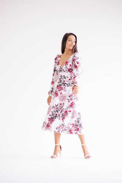 Young woman stands dressed in summer stylish floral pattern dress on white background. Full length body view. Isolated image. - Foto, afbeelding