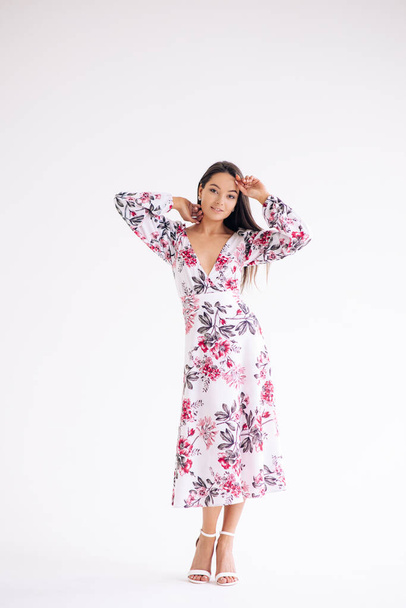 Jovem mulher fica vestida no verão elegante vestido padrão floral no fundo branco. Visão corporal de comprimento total. Imagem isolada. - Foto, Imagem